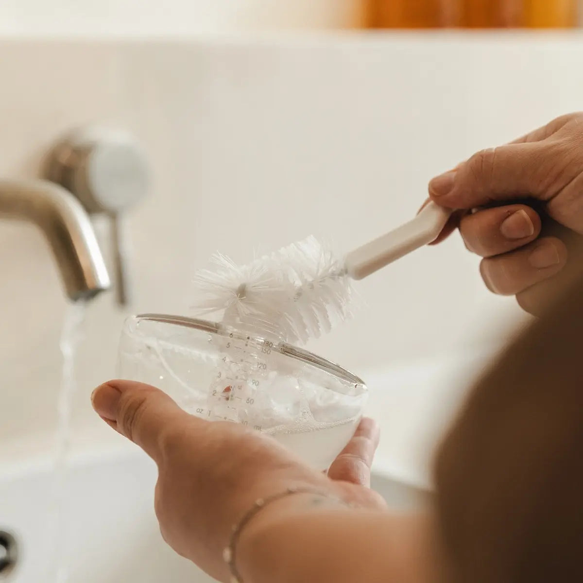 Mama maakt haar flesje schoon met de flessenborstel van Cura